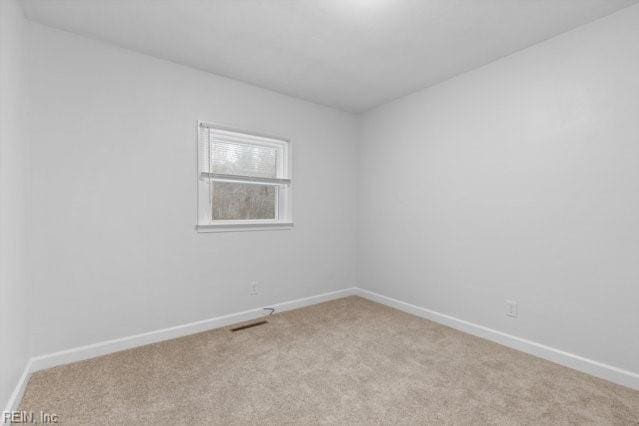 spare room with light carpet and baseboards