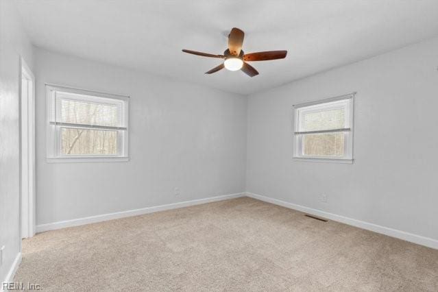 unfurnished room featuring light carpet, plenty of natural light, and baseboards