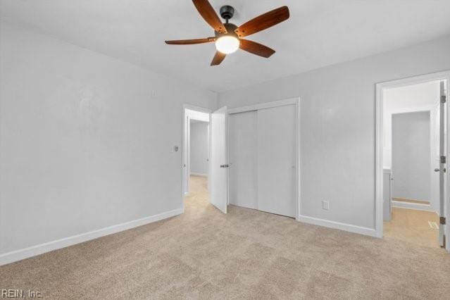 unfurnished bedroom with baseboards, ceiling fan, a closet, and light colored carpet