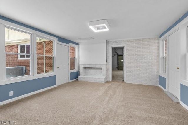 spare room with light carpet, a sunroom, and brick wall