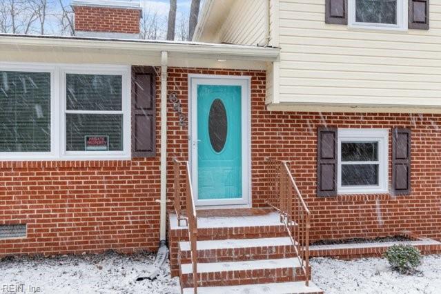 snow covered property entrance with brick siding