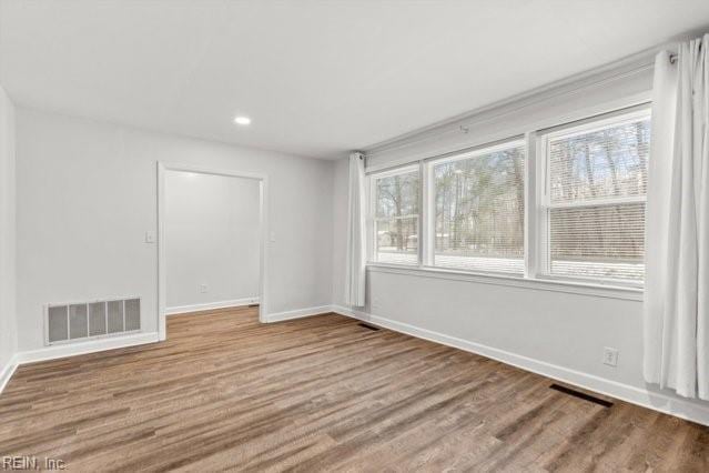 empty room with visible vents, baseboards, and wood finished floors