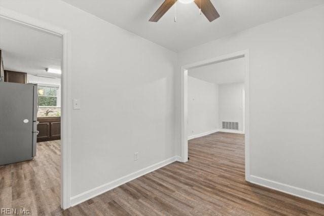 unfurnished room with visible vents, baseboards, ceiling fan, and wood finished floors