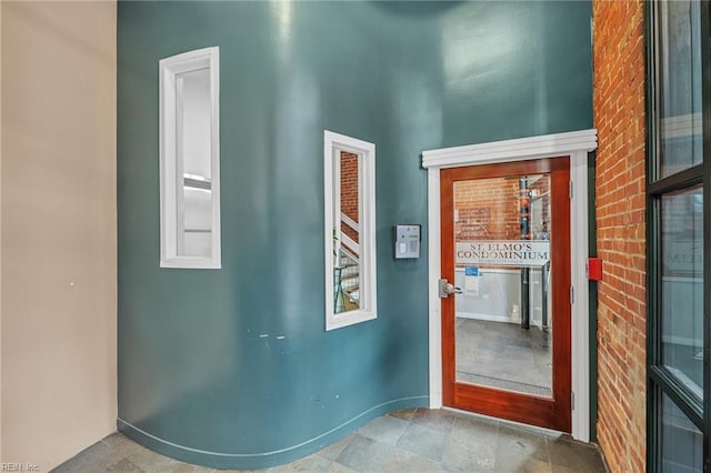 doorway with brick wall and baseboards