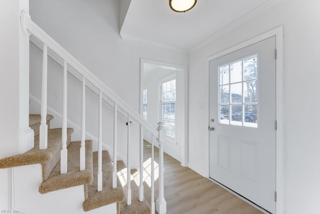 entryway featuring light wood-style floors, stairs, and ornamental molding