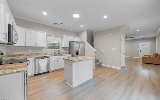 kitchen featuring a center island, appliances with stainless steel finishes, open floor plan, white cabinets, and a sink