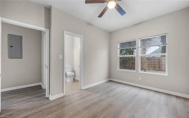 unfurnished bedroom with light wood-type flooring, electric panel, ensuite bath, and baseboards