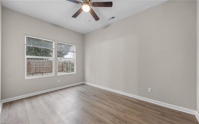 empty room with ceiling fan, light wood-style floors, visible vents, and baseboards