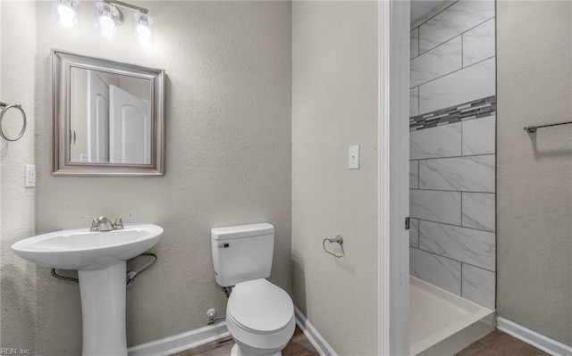 full bathroom with baseboards, a textured wall, a shower stall, and toilet