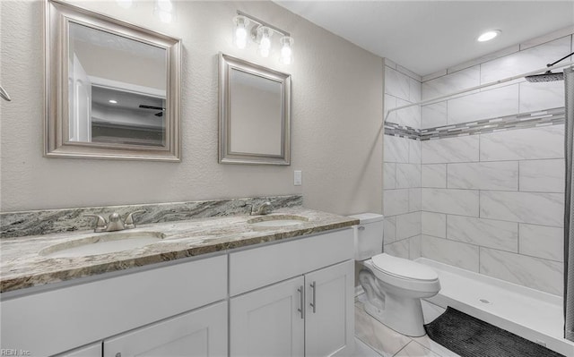 bathroom with toilet, a shower stall, double vanity, and a sink