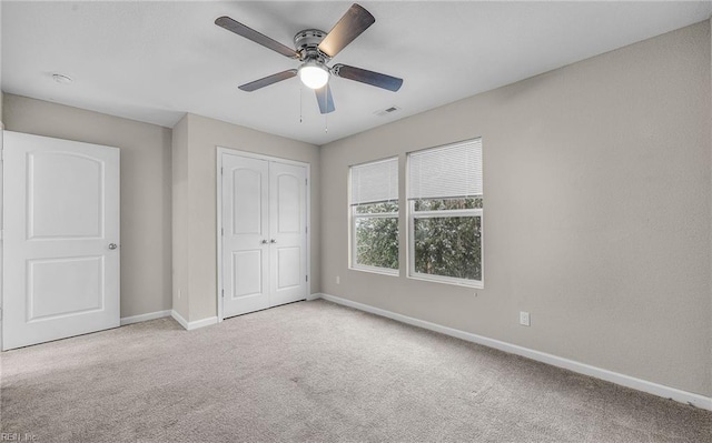 unfurnished bedroom featuring ceiling fan, light carpet, visible vents, baseboards, and a closet