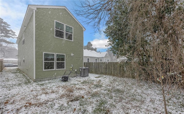 snow covered house featuring fence and central AC unit