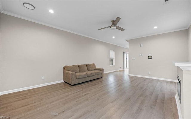 unfurnished room with ceiling fan, ornamental molding, light wood-type flooring, and baseboards