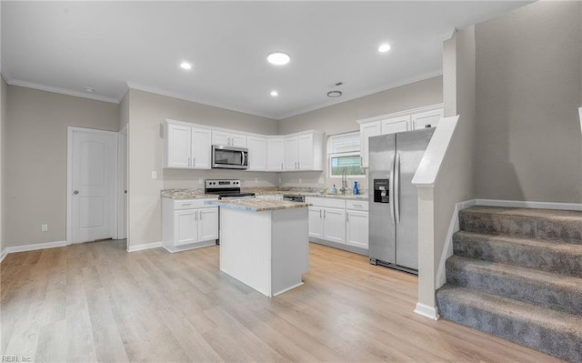 kitchen with light stone counters, stainless steel appliances, white cabinets, light wood-type flooring, and a center island