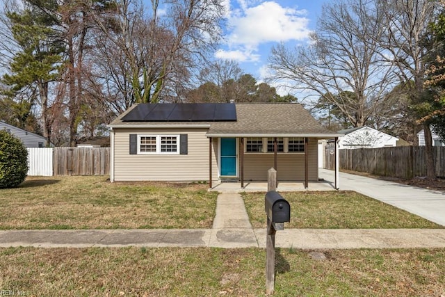 view of front of property with fence, a front lawn, and solar panels