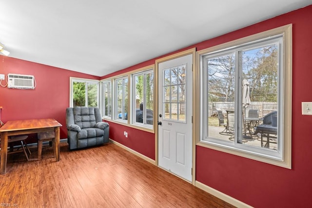 sitting room featuring light wood-type flooring, vaulted ceiling, baseboards, and a wall mounted AC