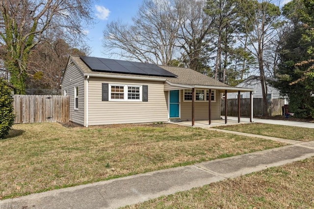 view of front facade with driveway, a front lawn, fence, and roof mounted solar panels