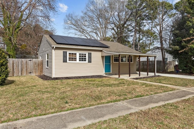 view of front of property featuring roof mounted solar panels, fence, and a front lawn