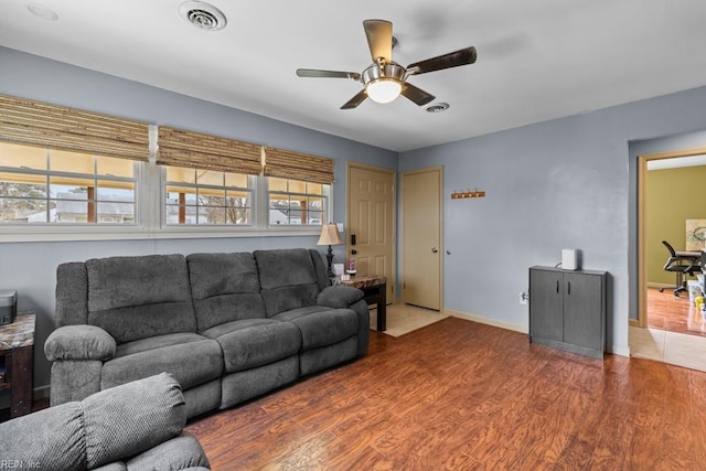 living room with ceiling fan, wood finished floors, visible vents, and baseboards