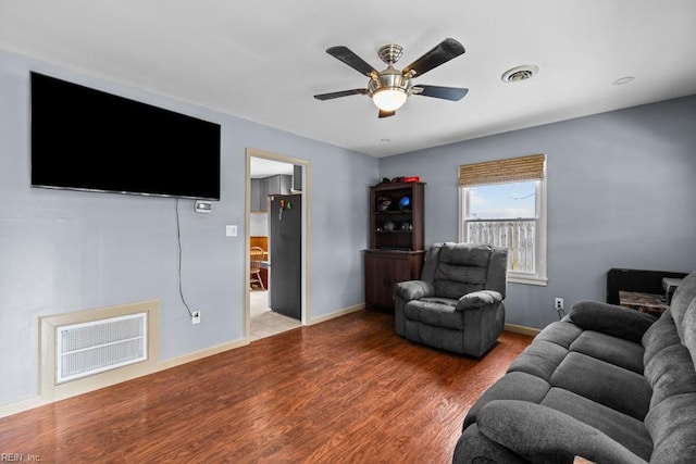 living room with visible vents, baseboards, and wood finished floors