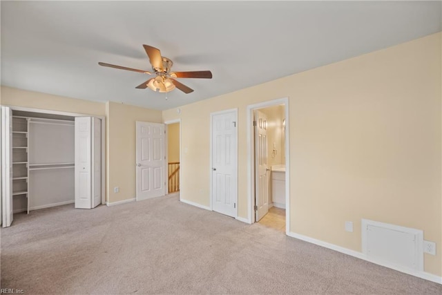 unfurnished bedroom featuring baseboards, light colored carpet, ensuite bath, ceiling fan, and a closet