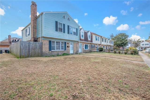 townhome / multi-family property with a residential view, brick siding, and fence