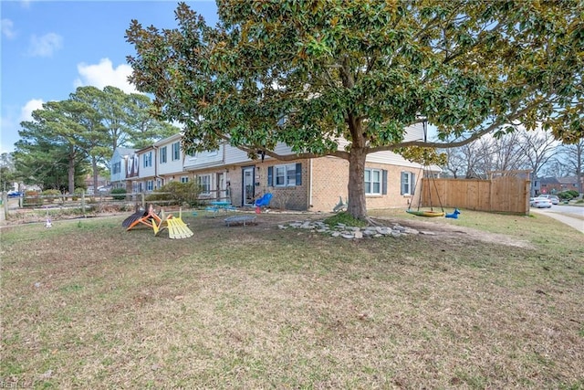 exterior space featuring brick siding, a front yard, and fence