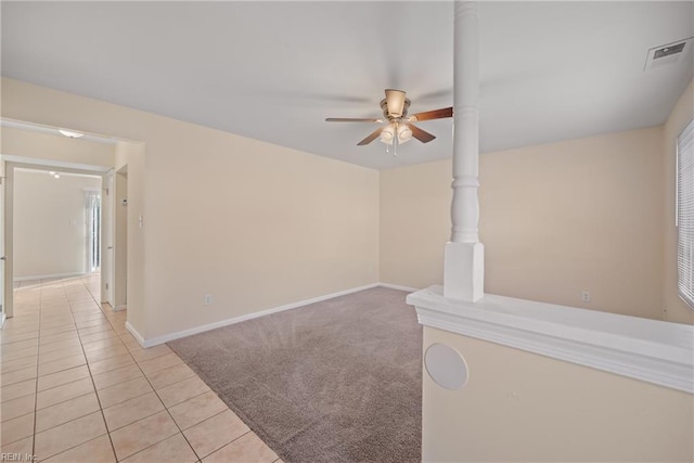 spare room featuring baseboards, visible vents, a ceiling fan, light colored carpet, and light tile patterned flooring