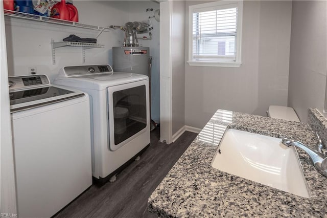 laundry area with washer and clothes dryer, water heater, dark wood-type flooring, a sink, and laundry area