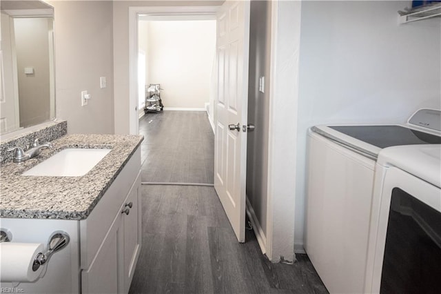 clothes washing area with dark wood-style floors, laundry area, separate washer and dryer, and a sink