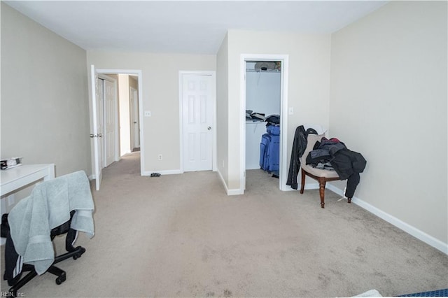 bedroom featuring baseboards, a walk in closet, a closet, and light colored carpet