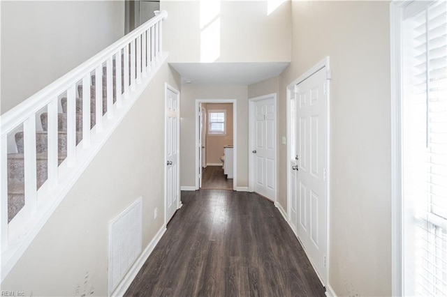 entrance foyer with baseboards, visible vents, dark wood-style floors, a high ceiling, and stairs