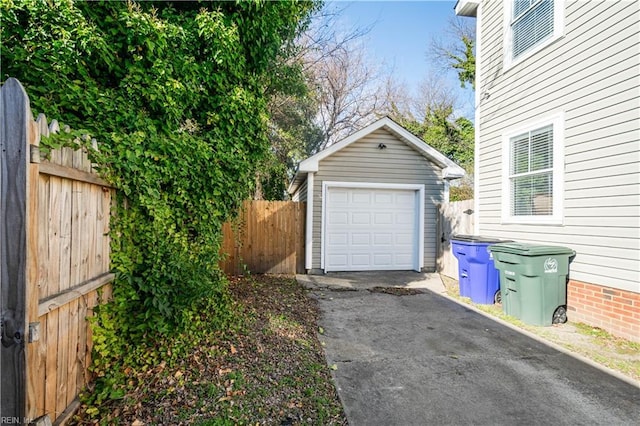 detached garage featuring aphalt driveway and fence