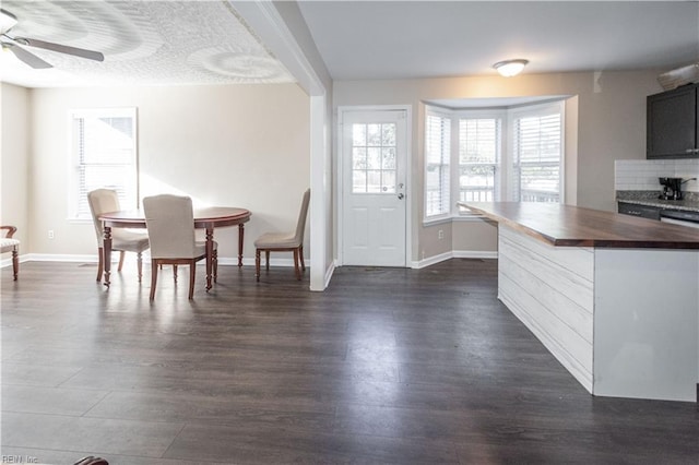 dining space featuring a ceiling fan, baseboards, and dark wood-type flooring