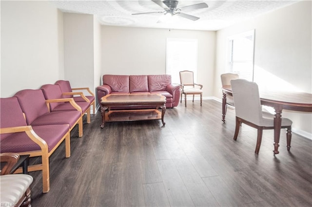 living area featuring ceiling fan, a textured ceiling, baseboards, and dark wood-style flooring