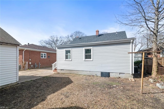 back of house with a chimney, a shingled roof, crawl space, and a patio area