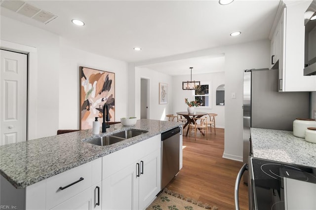 kitchen with arched walkways, visible vents, stainless steel appliances, white cabinetry, and a sink