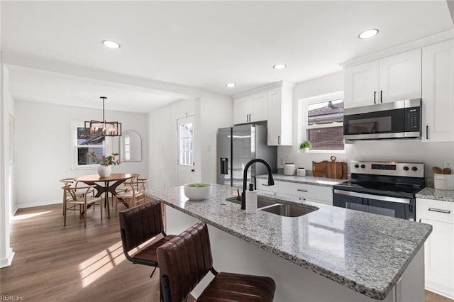 kitchen with dark wood-type flooring, a sink, white cabinetry, a kitchen breakfast bar, and appliances with stainless steel finishes