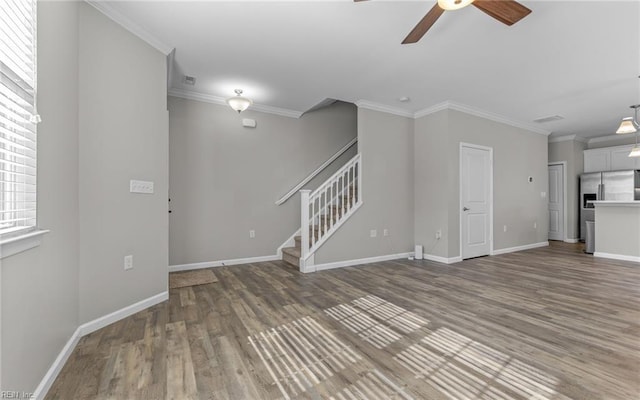 unfurnished living room featuring crown molding, a ceiling fan, wood finished floors, baseboards, and stairs