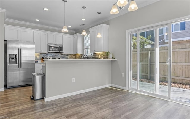 kitchen featuring backsplash, stainless steel appliances, crown molding, and wood finished floors