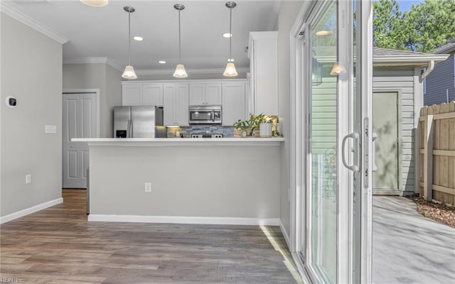 kitchen with stainless steel appliances, white cabinetry, and ornamental molding