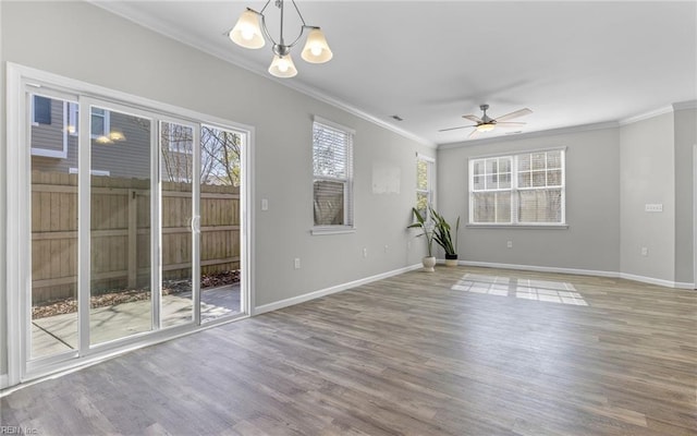 unfurnished room with ornamental molding, a healthy amount of sunlight, wood finished floors, and baseboards