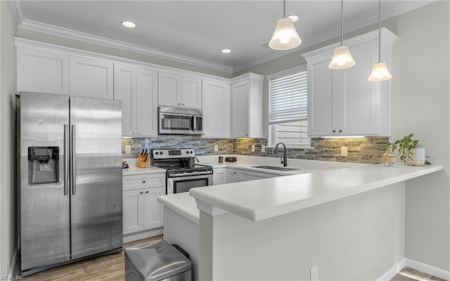 kitchen featuring a peninsula, a sink, light countertops, appliances with stainless steel finishes, and tasteful backsplash