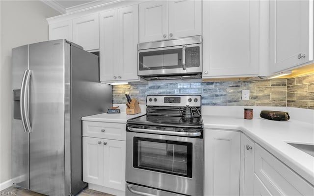 kitchen with crown molding, light countertops, decorative backsplash, appliances with stainless steel finishes, and white cabinetry