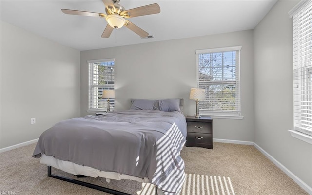 carpeted bedroom with visible vents, a ceiling fan, and baseboards