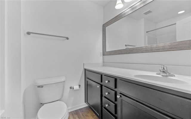 bathroom featuring baseboards, visible vents, toilet, wood finished floors, and vanity