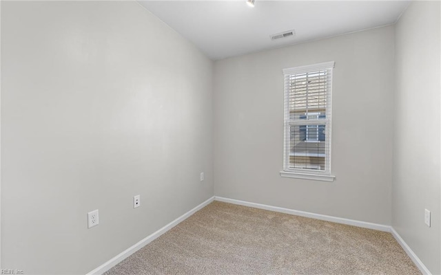 empty room with baseboards, visible vents, and light colored carpet