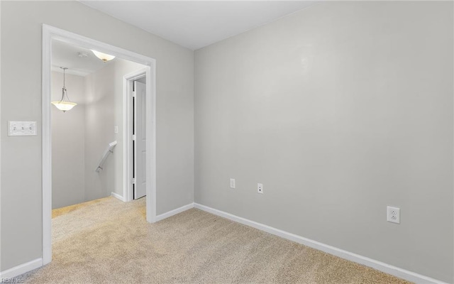 empty room featuring light carpet and baseboards