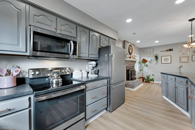 kitchen with stainless steel appliances, hanging light fixtures, and dark countertops