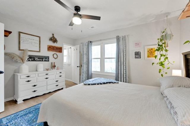 bedroom featuring ceiling fan, baseboards, visible vents, and light wood-style floors